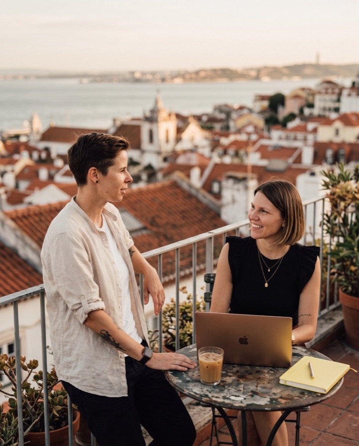 KI-Bild: Franka und Kathi an einem Bistrotisch auf einer Dachterrasse über Lissabon